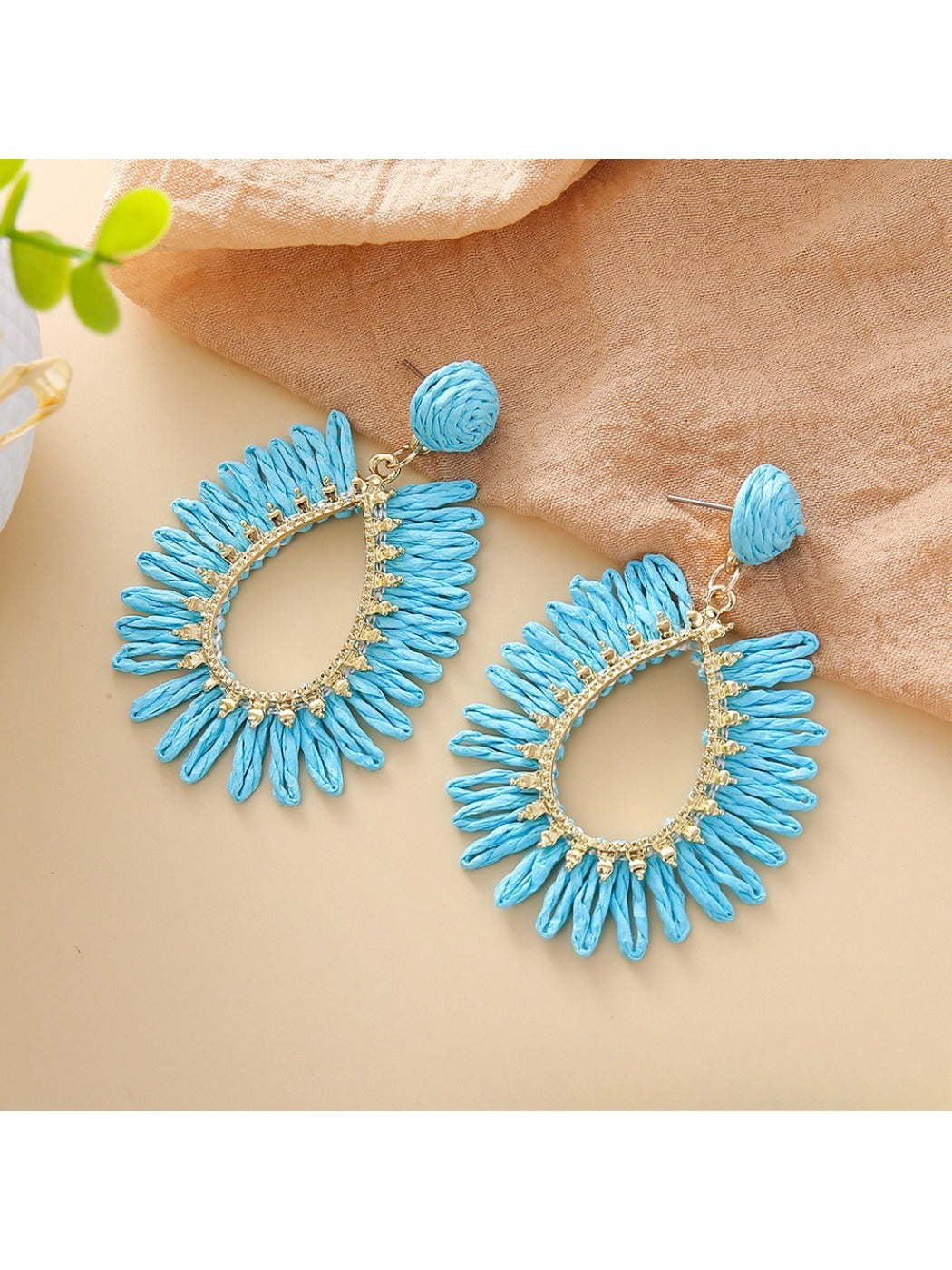Earedge raffia teardrop hollow earrings hanging on a jewelry stand