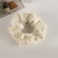 Gifty floral scrunchie laid flat, emphasizing its layered tulle and fabric flowers