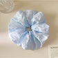 Gifty scrunchie placed on a white surface, showcasing its bright multicolor checkered pattern