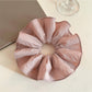 Soft pink fabric scrunchie with gathered elastic design on white background