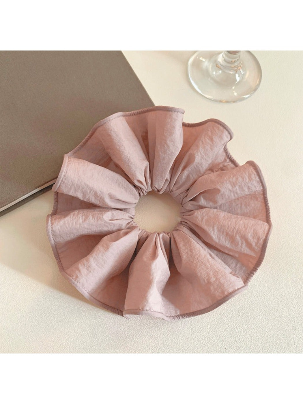 Soft pink fabric scrunchie with gathered elastic design on white background