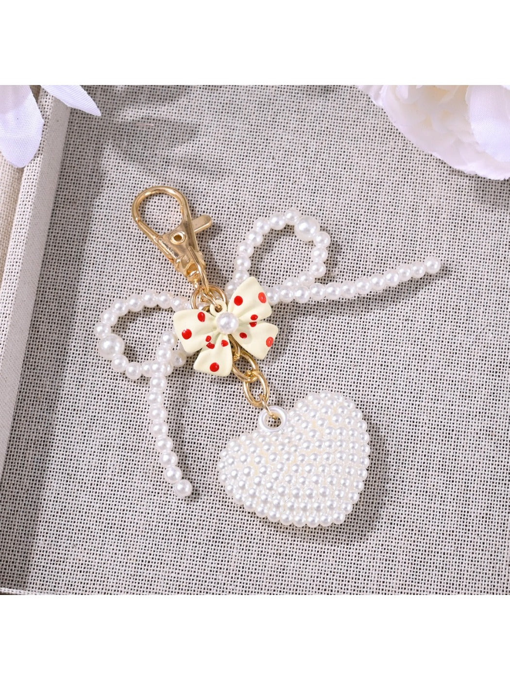 Keypus bow heart shaped keychain in pink with gold ring on white background