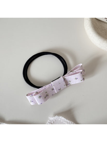 Gifty hair tie with bow placed next to matching pink accessories