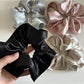 Gifty satin scrunchie displayed flat with gentle folds highlighting satin sheen