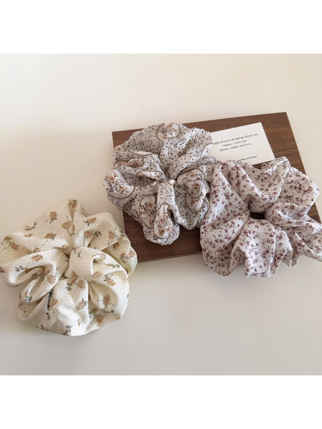 Close-up of Gifty floral print scrunchie with pink and green flowers on fabric