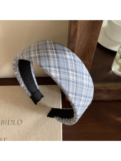 Model adjusting the wide plaid headband while smiling