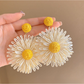 Model showcasing colorful floral raffia drop earrings with short hair