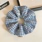Blue plaid scrunchie stretched to show elastic band inside