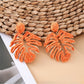 Close-up of raffia woven hollow leaf shaped earrings highlighting woven details