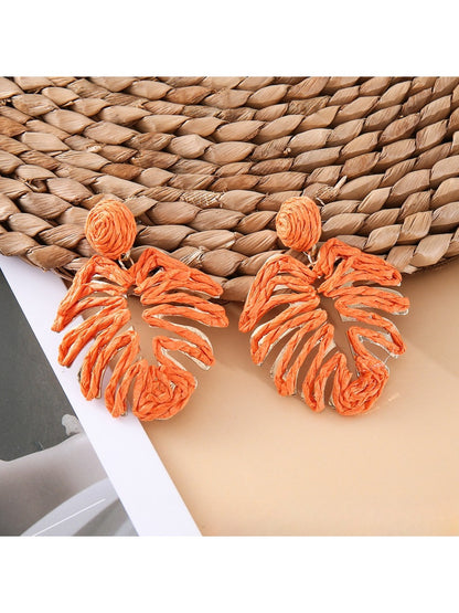 Close-up of raffia woven hollow leaf shaped earrings highlighting woven details