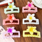 Beau square ombre flower shaped claw clip in pink and purple gradient on white background
