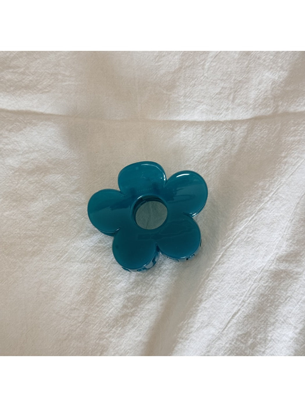Top view of beige flower shaped claw clip showing symmetrical petals