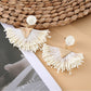Flat lay of earedge raffia drop earrings with natural elements and accessories