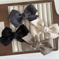 Beau solid satin bow hair clip on white background showing front view