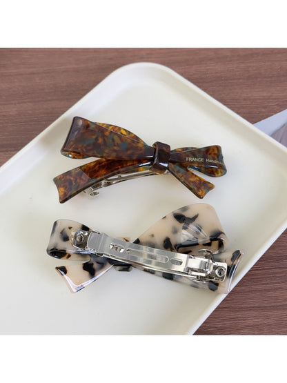 Close-up of Beau bow-shaped hair clip showing acetate texture and glossy finish
