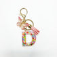 Letter pendant with butterfly charm on a silver keyring on a marble surface