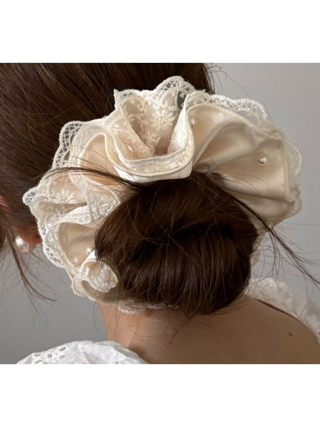 Beige satin scrunchie displayed on a wooden surface