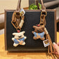Fabric little bear shaped keychain with stitched details on a white background
