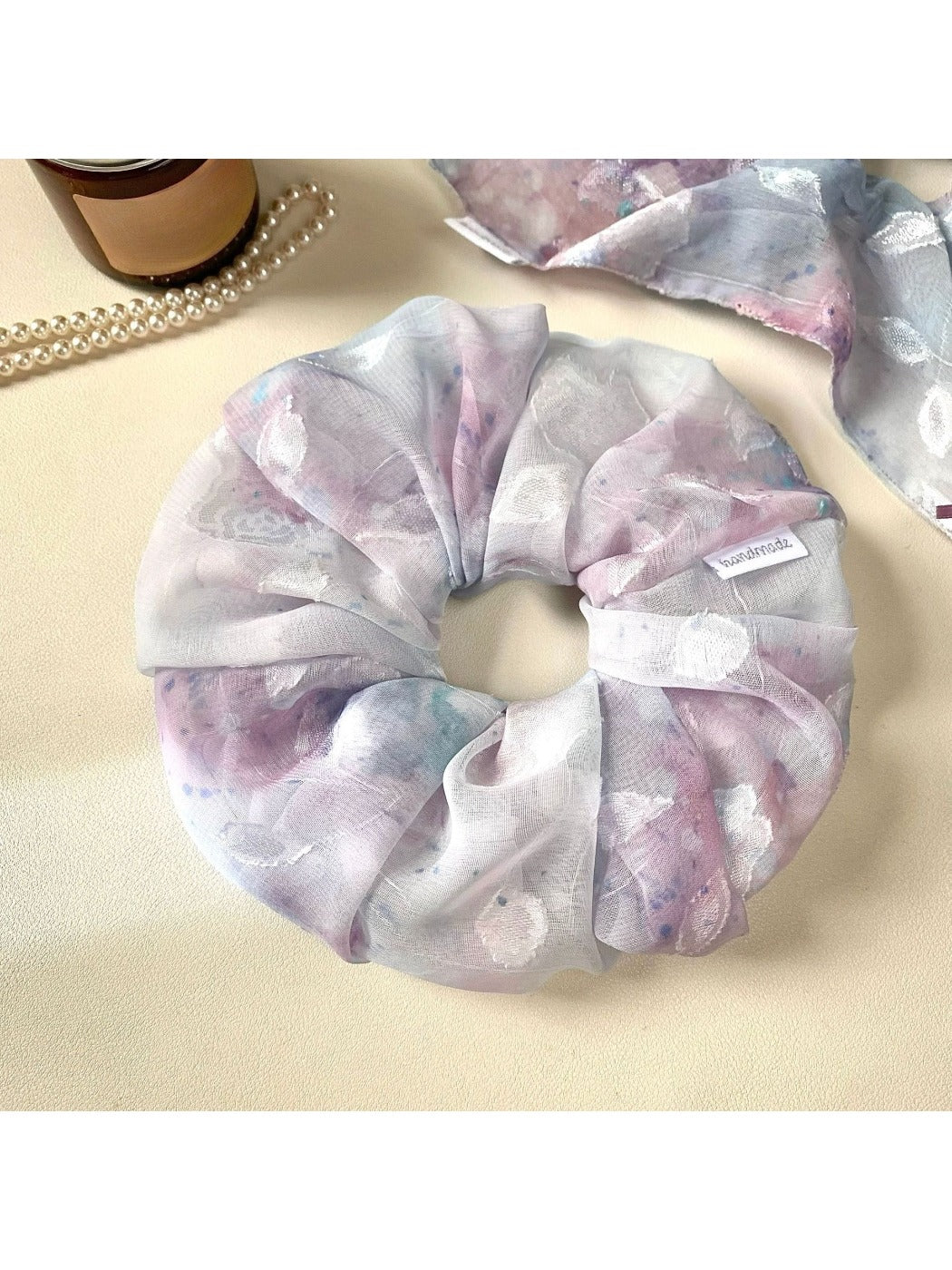 Gifty scrunchie wrapped around a ponytail on a model with casual outfit