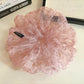 Pink tulle scrunchie styled on a wrist with visible floral design