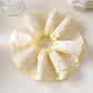 Gifty color block scrunchie in beige and brown tones against a soft pastel background