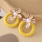 Earedge round floral pendant earrings placed on a wooden surface