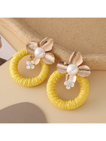 Earedge round floral pendant earrings placed on a wooden surface