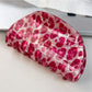 Beau pink leopard print half round claw clip next to matching hair accessories
