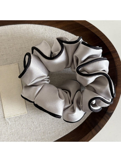 Ruffled satin scrunchie stretched slightly to show elasticity and fabric texture