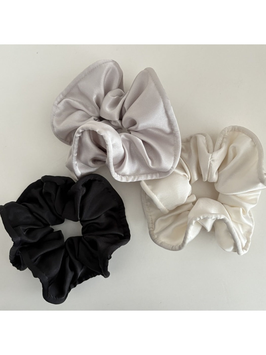 Side view of Gifty satin scrunchie highlighting its gathered silky fabric