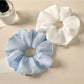 Close-up of a minimalist solid color ruched scrunchie on a white background