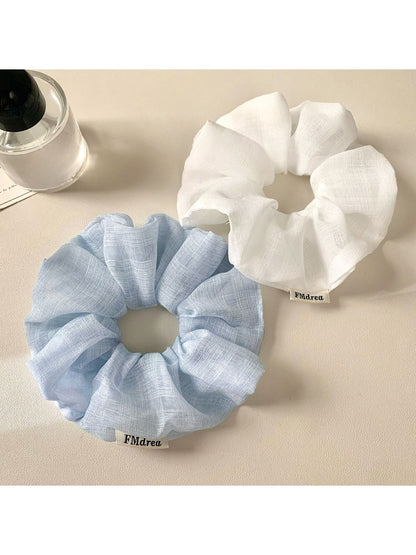 Close-up of a minimalist solid color ruched scrunchie on a white background