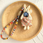 Keypus fabric doll keychain hanging from a backpack strap