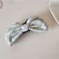 Model styling hair with Beau elegant bow banana clip, side profile