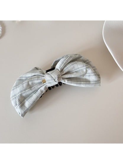 Model styling hair with Beau elegant bow banana clip, side profile