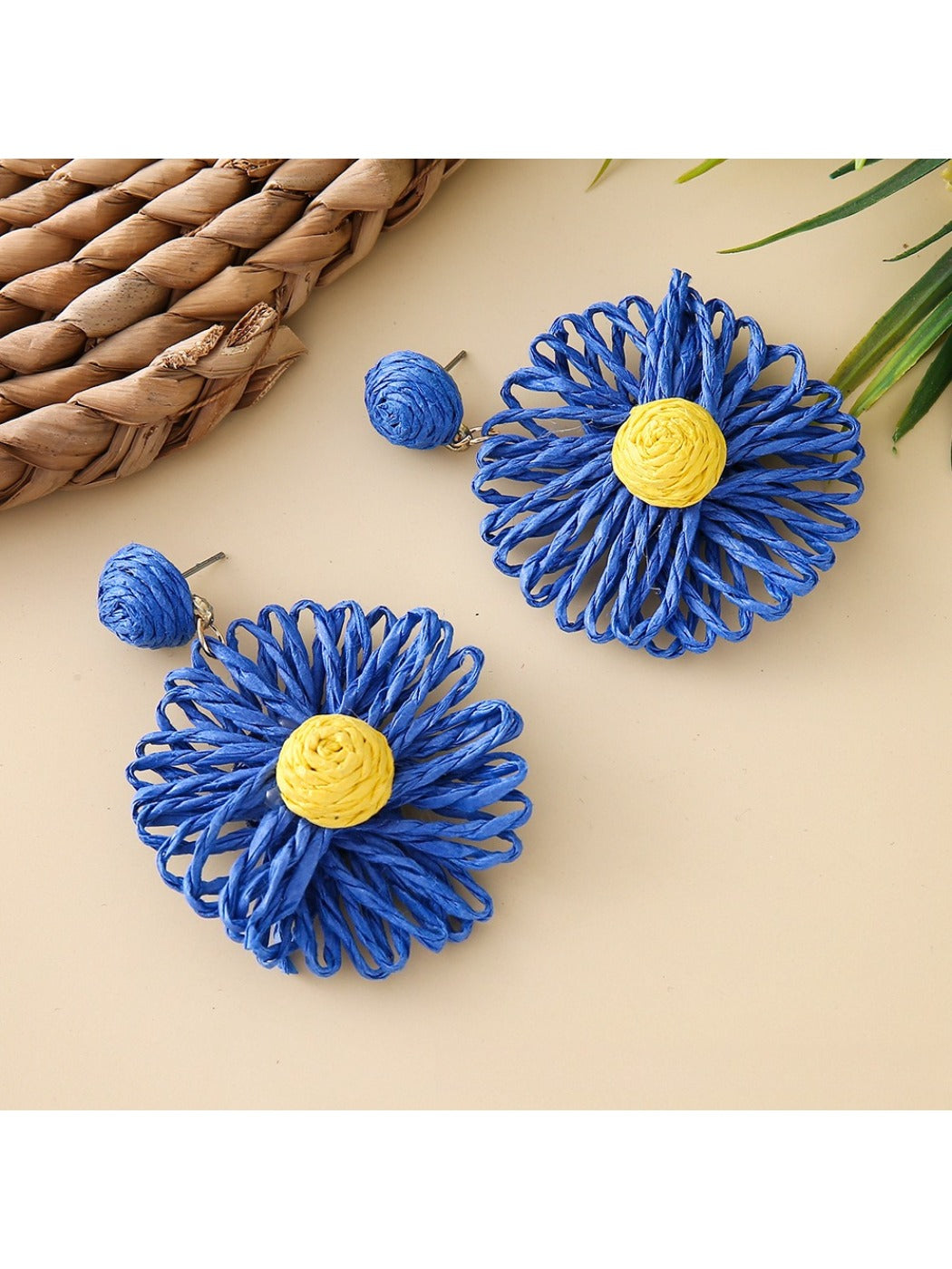 Raffia sunflower earrings hanging on a wooden display stand