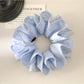 Blue polka dot scrunchie styled in a ponytail on model