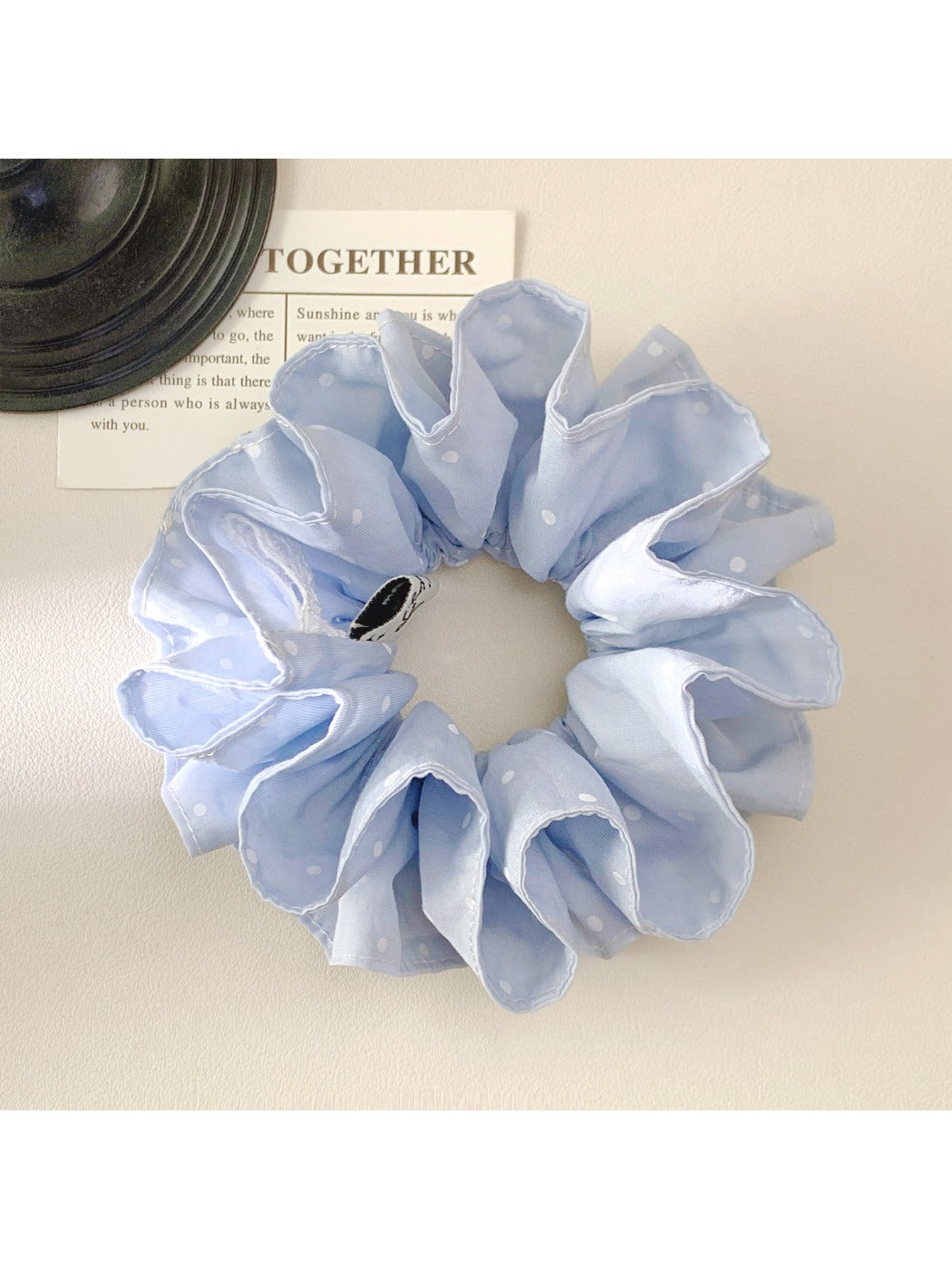 Blue polka dot scrunchie styled in a ponytail on model