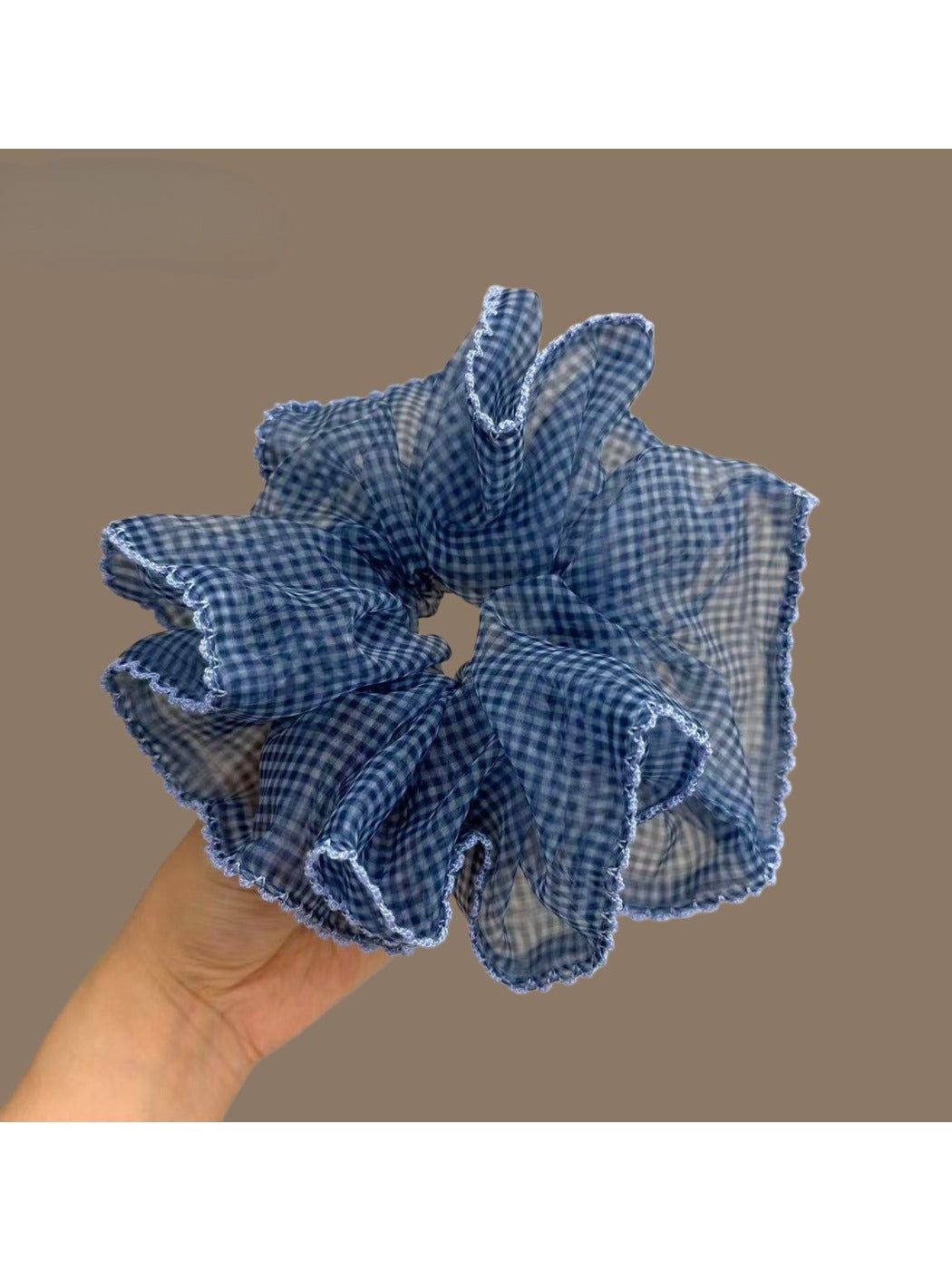 Blue plaid tulle scrunchie styled on a wrist with soft lighting