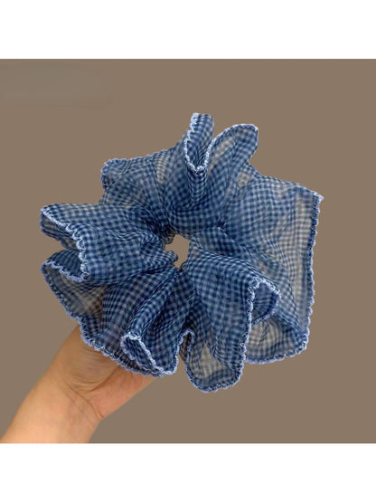 Blue plaid tulle scrunchie styled on a wrist with soft lighting