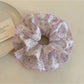 Close-up of purple floral fabric scrunchie showing texture and pattern