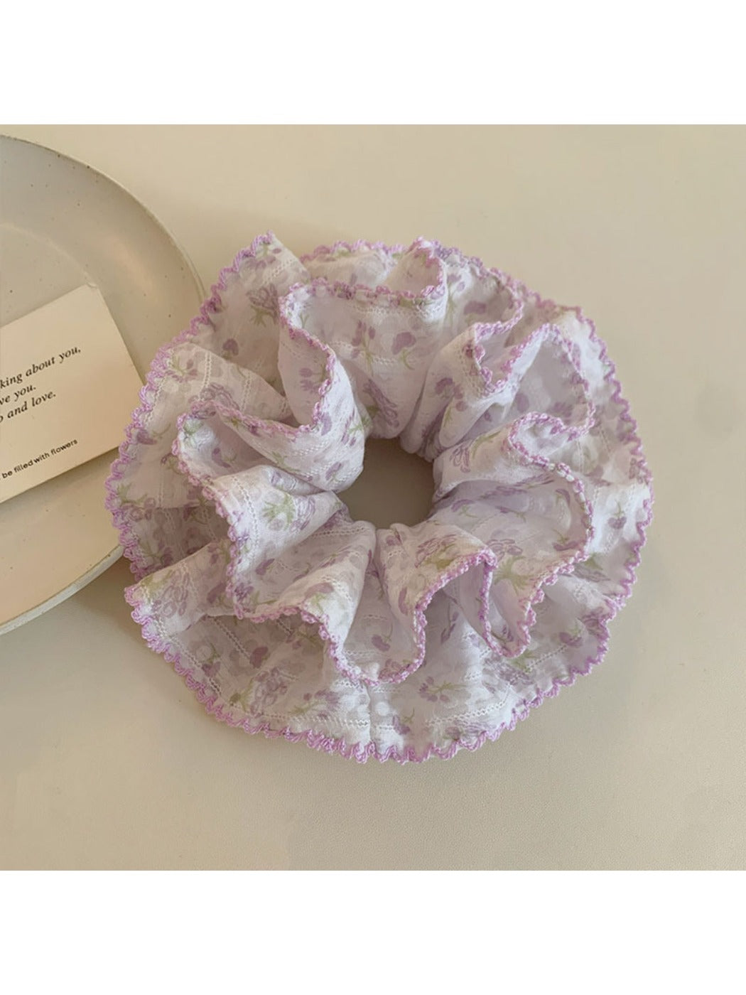 Close-up of purple floral fabric scrunchie showing texture and pattern