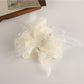 Gifty ruched scrunchie in soft pink fabric with bow accent on a wooden surface