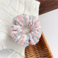 Flat lay of assorted colorful scrunchies and headbands on a neutral background