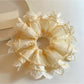 Beige tulle scrunchie with delicate lace trim on a white background