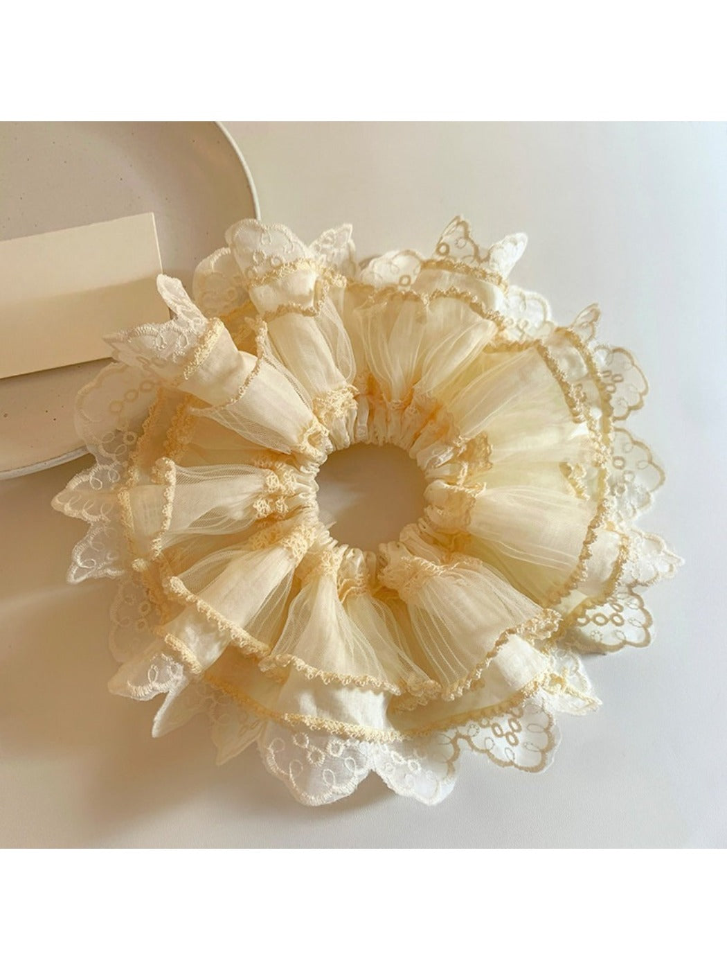 Beige tulle scrunchie with delicate lace trim on a white background