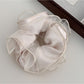 Gifty scrunchie worn on wrist highlighting satin fabric and ruching