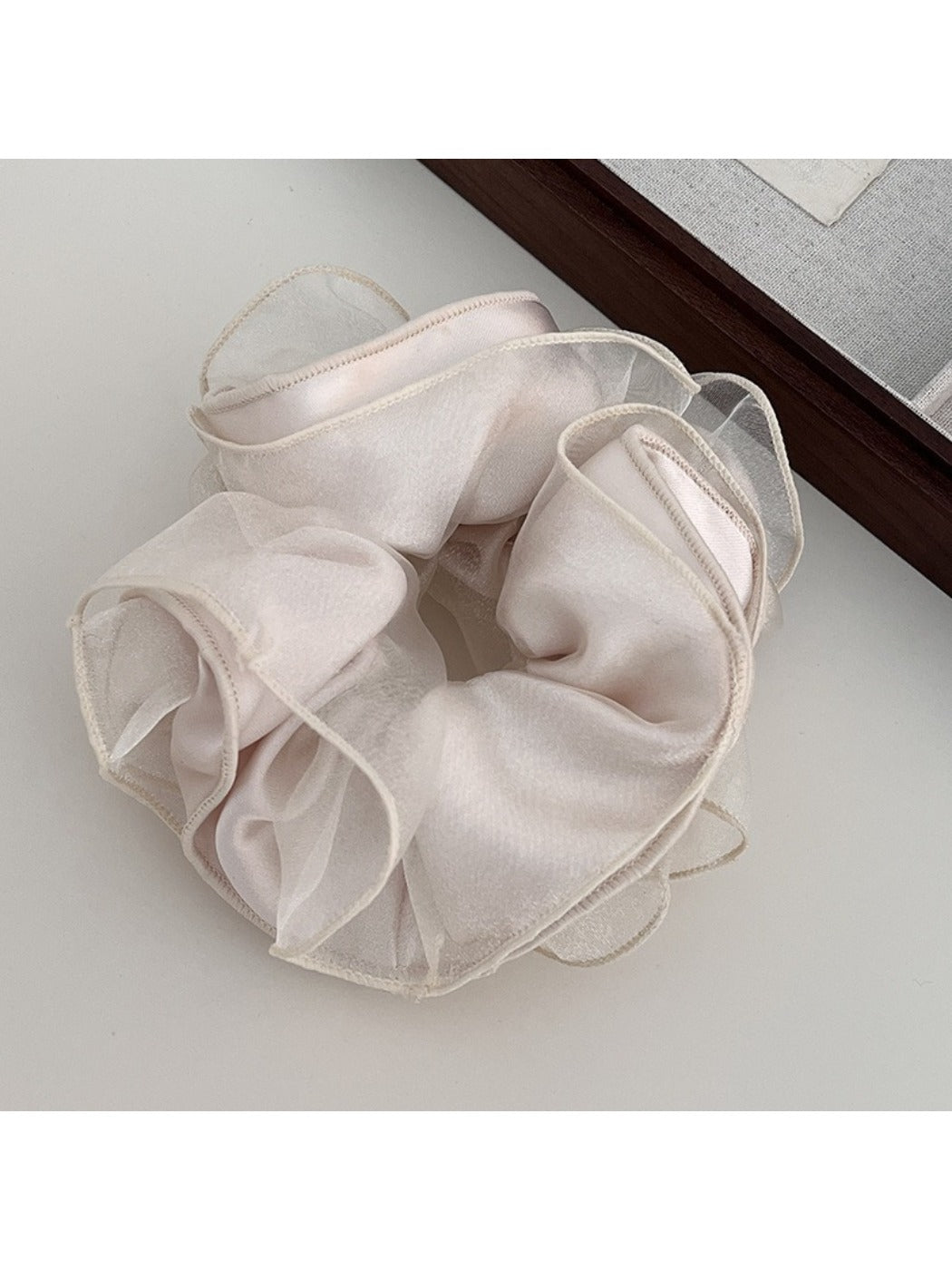Gifty scrunchie worn on wrist highlighting satin fabric and ruching