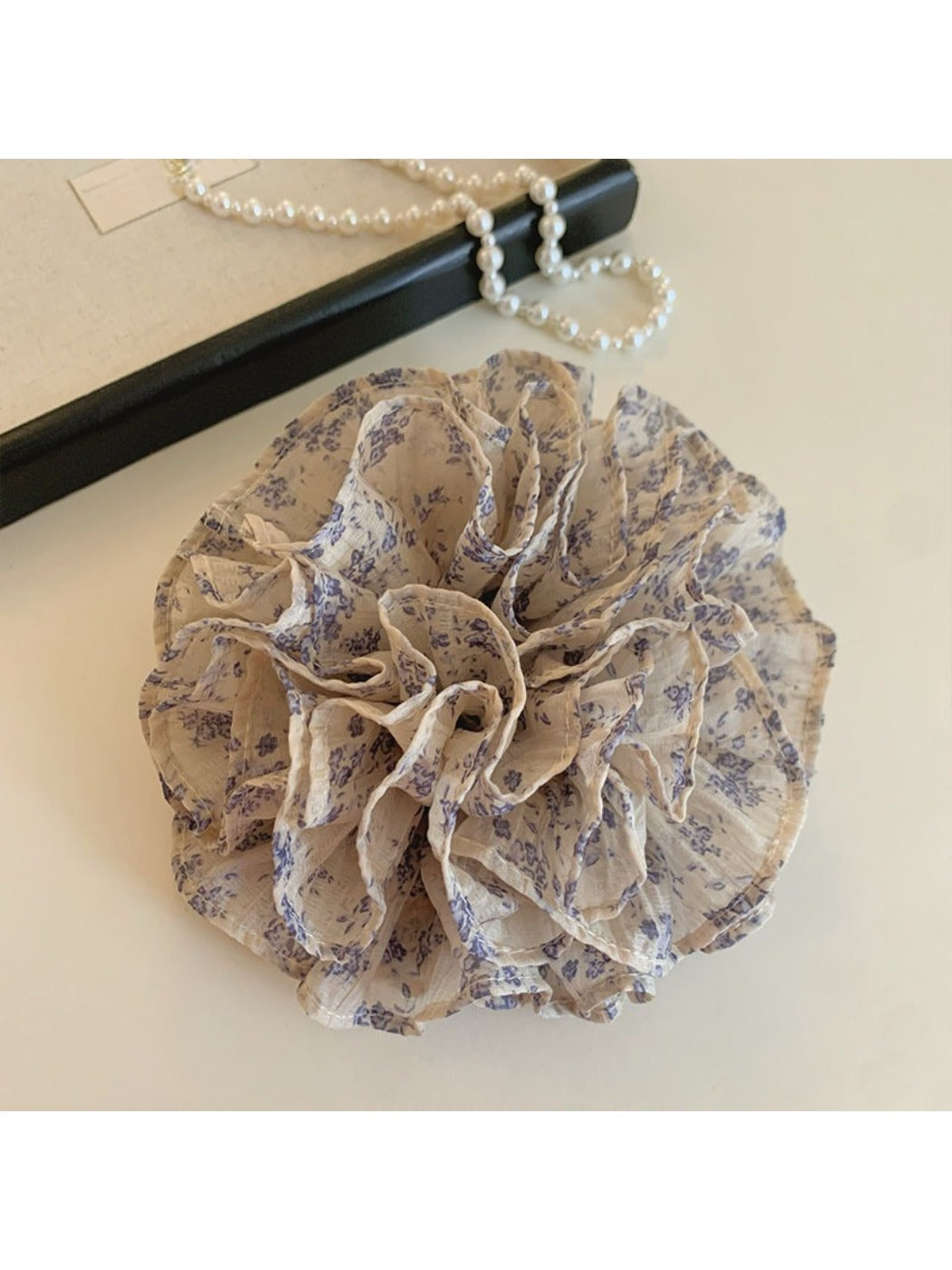 Gifty scrunchie styled on a wrist highlighting vintage floral print and gathered fabric