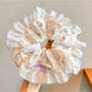 Gifty scrunchie wrapped around a ponytail in brown hair highlighting floral print